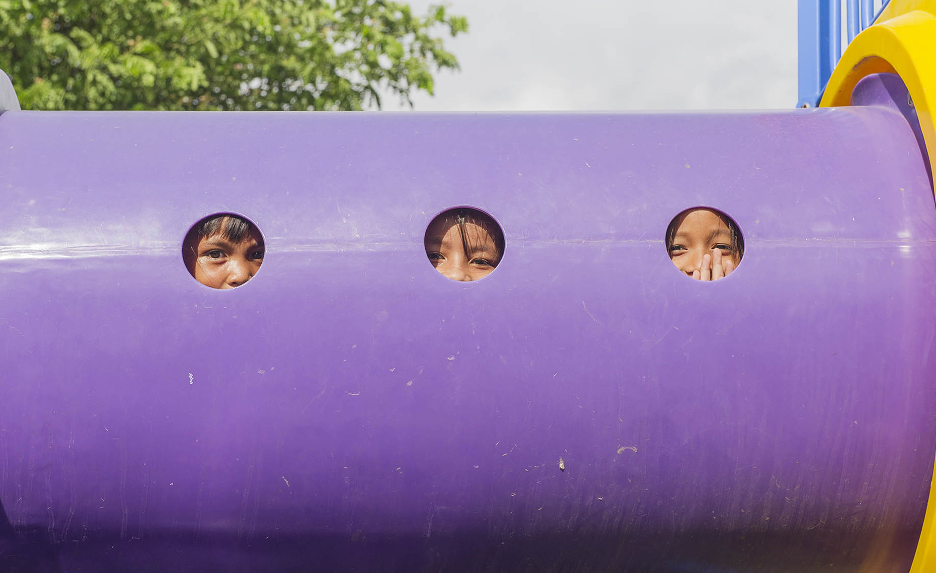 LAT_PhotoReporters_youngsters-peek-from-playground-equipment-at-Sunrise-Childrens-Village_Phnom-Penh_Cambodia