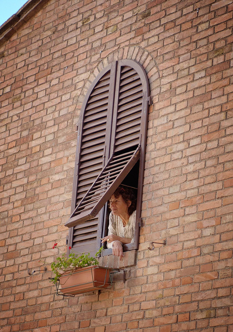 TRA_PhotoReporters_woman-peerfing-from-window_Casole-D-Elsa_Italy